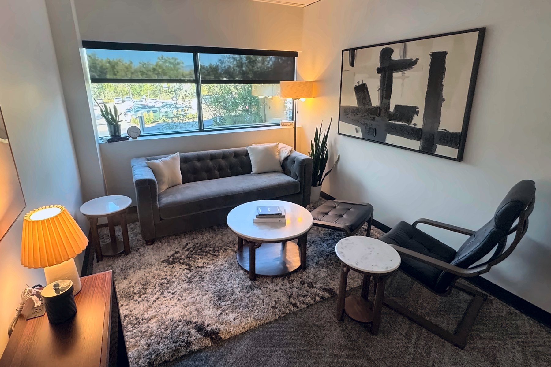 Therapy office in Wheat Ridge with a sofa, armchair, warm lamps, and a window